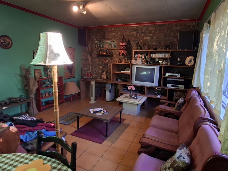 A living room featuring an exposed brick wall, built-in shelving, and tiled flooring, offering a dated aesthetic ready for modernization.