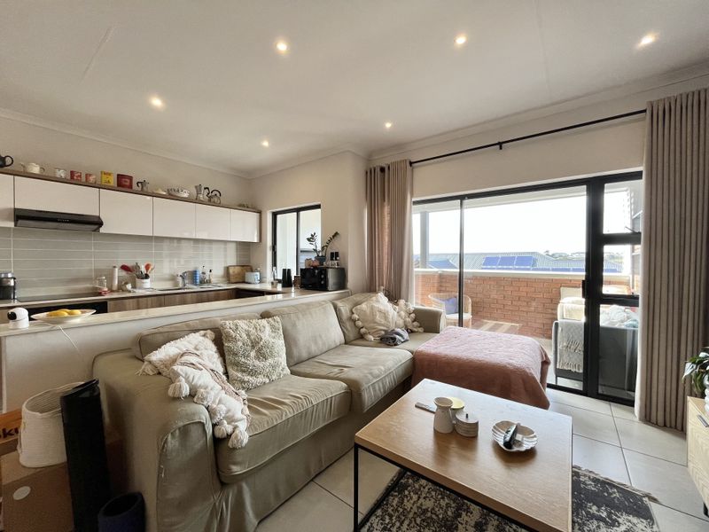 Open-plan living area featuring a modern kitchen with built-in cabinetry and seamless access to a private balcony through large sliding glass doors.