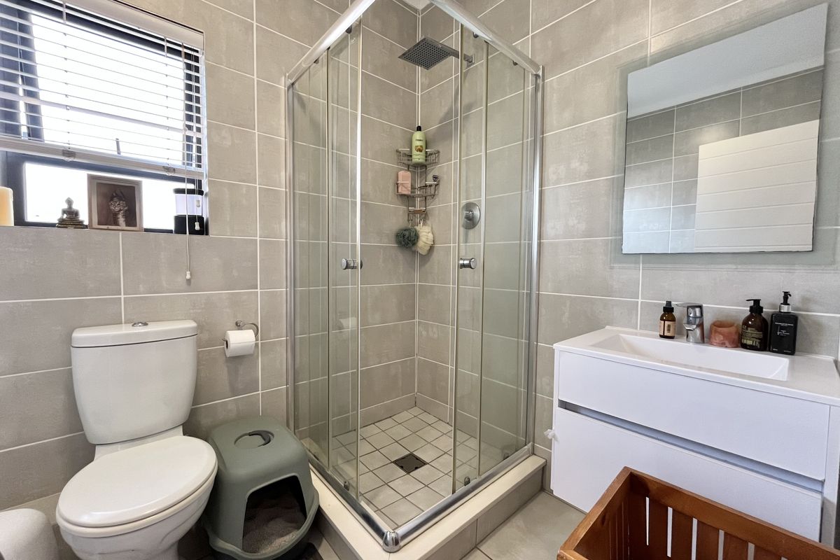 A modern bathroom featuring a glass-enclosed shower, a sleek vanity unit, and neutral wall tiling.