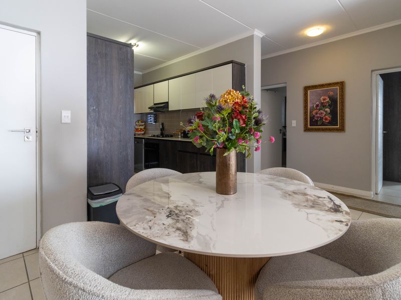 An open-plan living and kitchen area featuring modern dark and light cabinetry, tiled flooring, and a functional layout suitable for dining and entertaining.