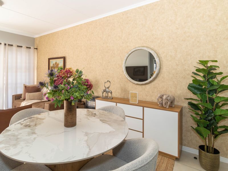 A well-maintained living area featuring textured wallpaper, coving, and access to an outdoor space through a sliding glass door.