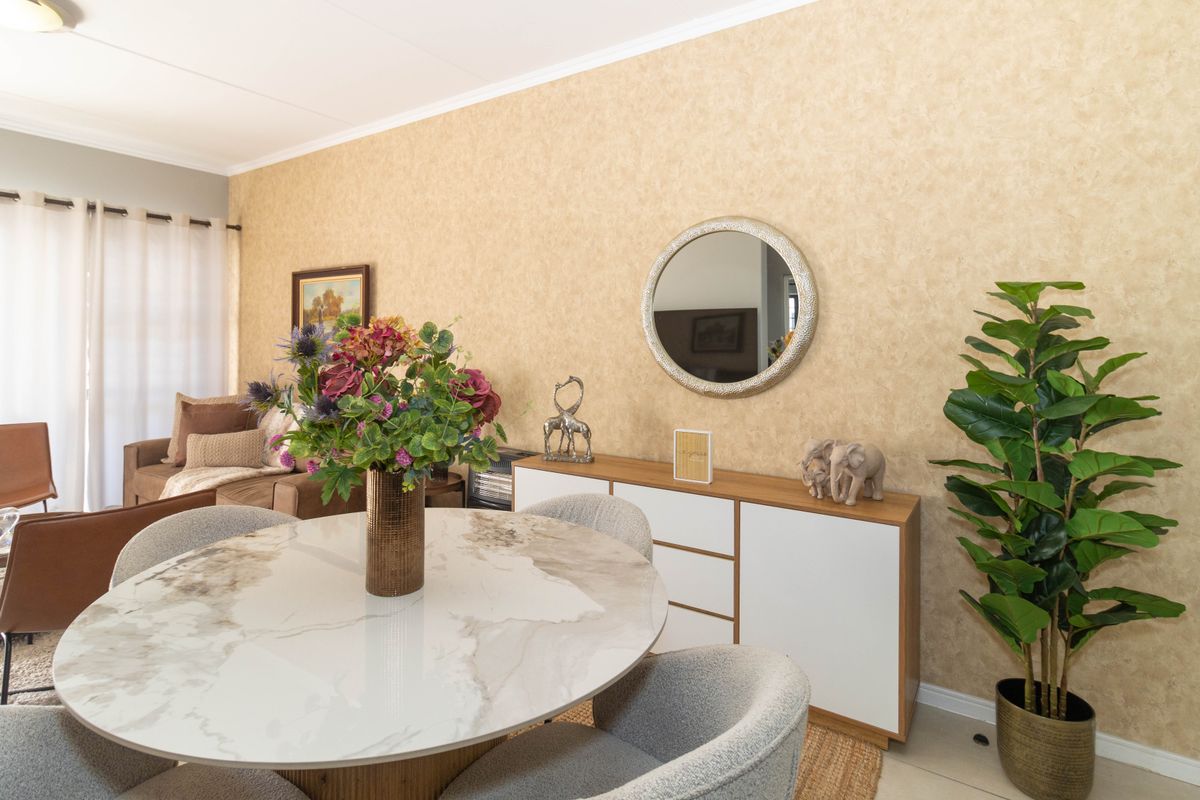 A well-maintained living area featuring textured wallpaper, coving, and access to an outdoor space through a sliding glass door.