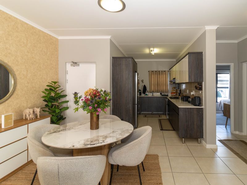 Open-plan living and dining area featuring tiled flooring, modern built-in kitchen cabinetry, and neutral wall finishes.