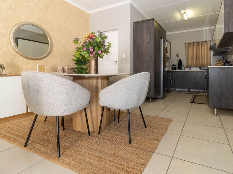 Open-plan living and dining area featuring tiled floors and a modern kitchen with built-in cabinetry and integrated appliances.