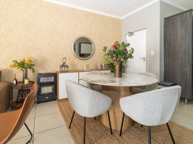 A well-maintained dining area featuring tiled flooring, textured feature wallpaper, and a built-in storage cupboard.
