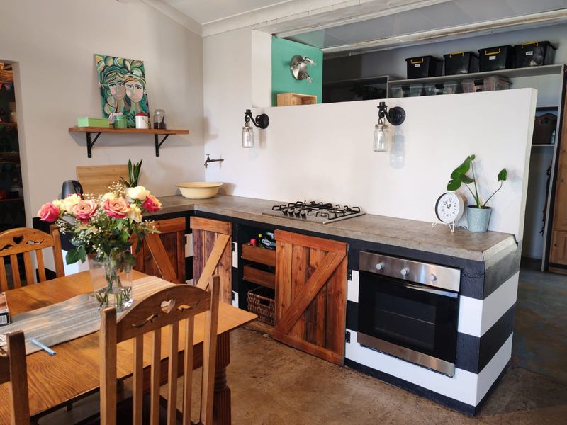 A rustic-style kitchen featuring a concrete countertop, built-in gas hob, oven, and custom wooden cabinetry with a unique black and white striped base.