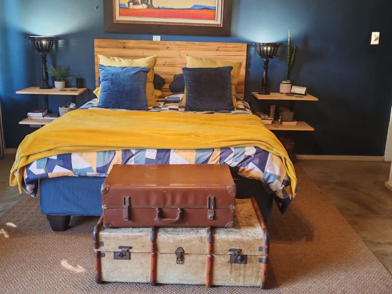 A cozy bedroom featuring a dark accent wall, floating wooden bedside shelves, and a central pendant light fixture.
