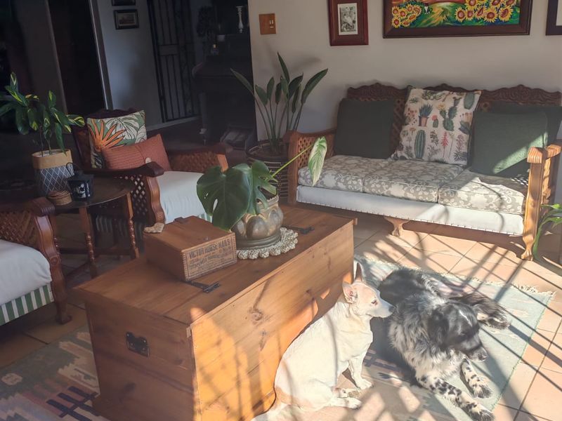 A sunlit living room featuring tiled flooring and a classic wrought iron chandelier, offering a comfortable and inviting space.