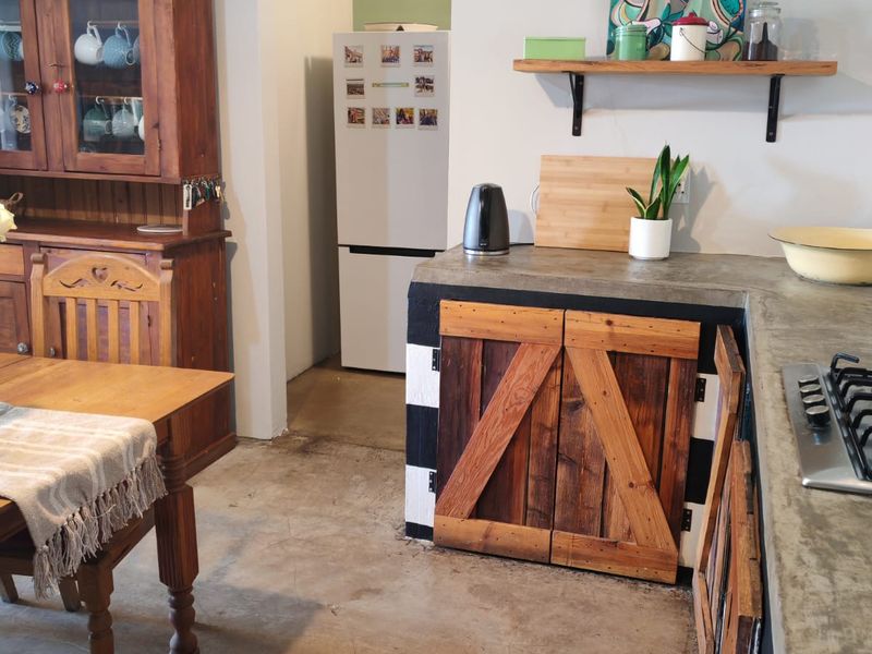 Rustic kitchen featuring concrete countertops, custom timber cabinetry, and a built-in gas hob, offering a unique industrial-style aesthetic.