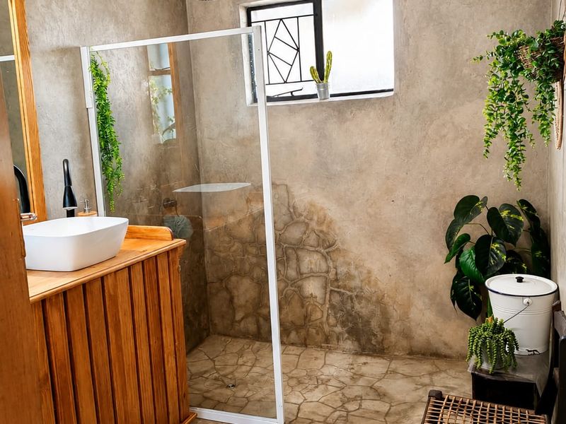 A rustic-style bathroom featuring a walk-in shower with a rain shower head, a wooden vanity with a vessel sink, and textured wall finishes.