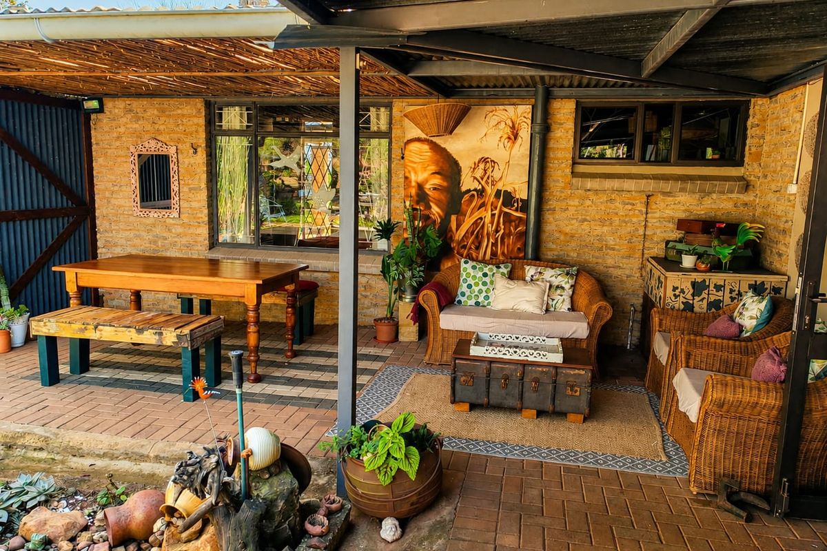 A covered outdoor patio area featuring brick walls, paved flooring, and a corrugated metal roof, providing a functional space for outdoor dining and relaxation.