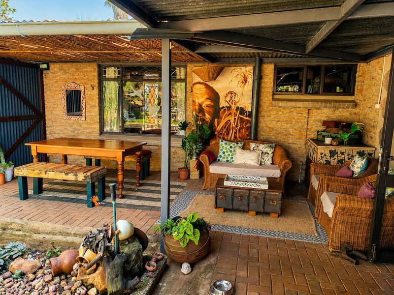 A covered outdoor patio area featuring brick walls, paved flooring, and a corrugated metal roof, providing a functional space for outdoor dining and relaxation.