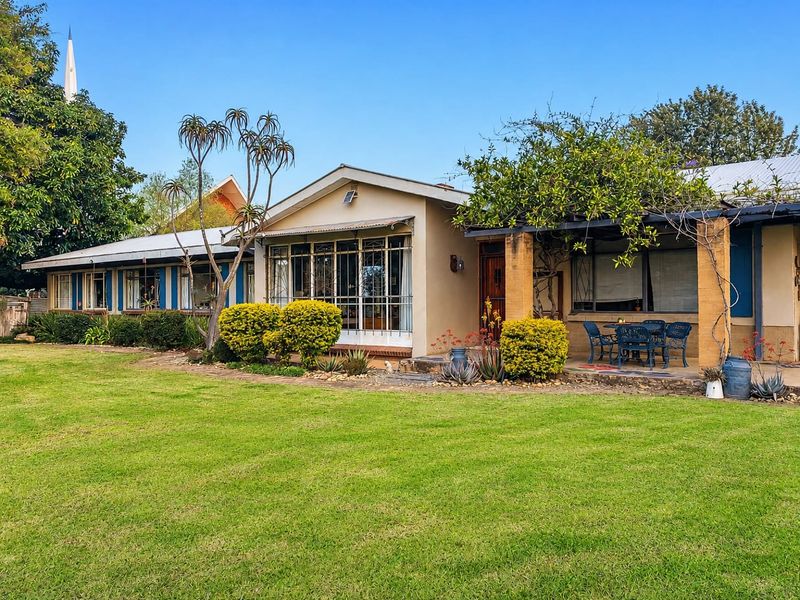 Rear view of the house featuring a covered patio area, established garden, and classic architectural details with security features.