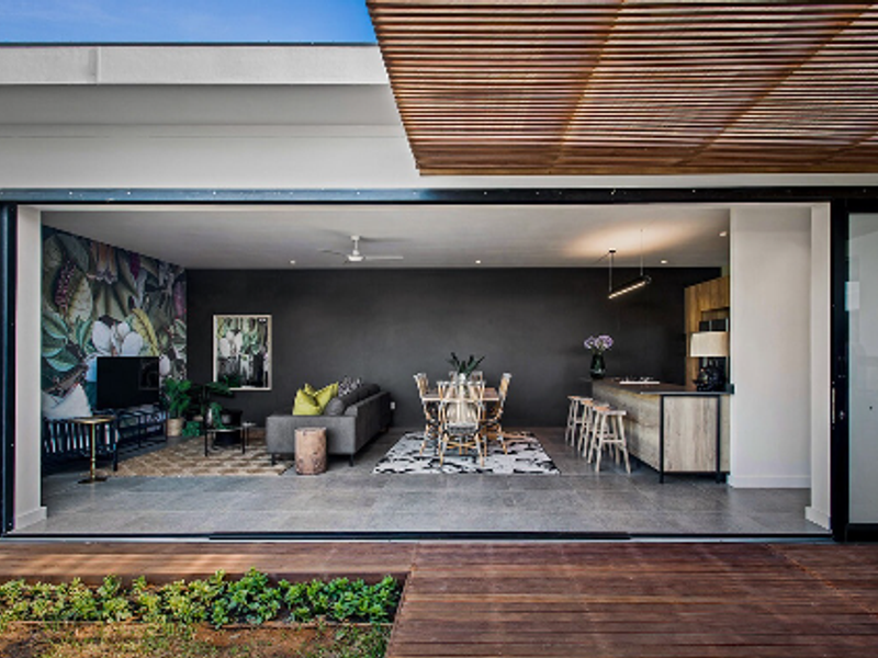 Modern open-plan living and dining area featuring large format tiles, a kitchen island, and seamless indoor-outdoor flow through expansive sliding glass doors.