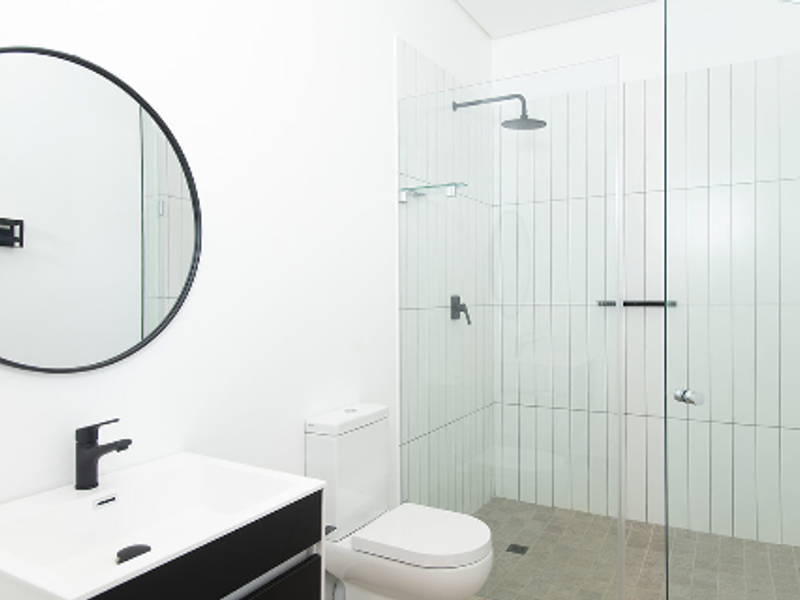 Modern bathroom featuring a sleek vanity, walk-in shower with rain shower head, and contemporary black fixtures.