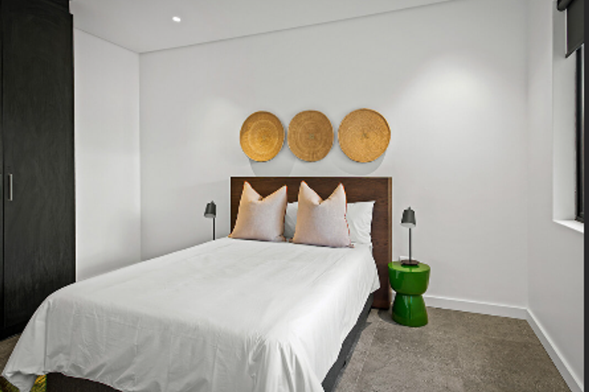 A modern, well-maintained bedroom featuring neutral walls, built-in cabinetry, recessed lighting, and a roller blind.