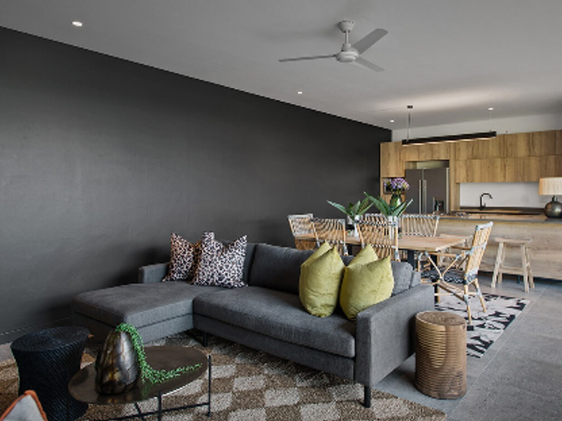 Modern open-plan living and dining area featuring a contemporary kitchen with wood-finish cabinetry, tiled floors, and recessed lighting.