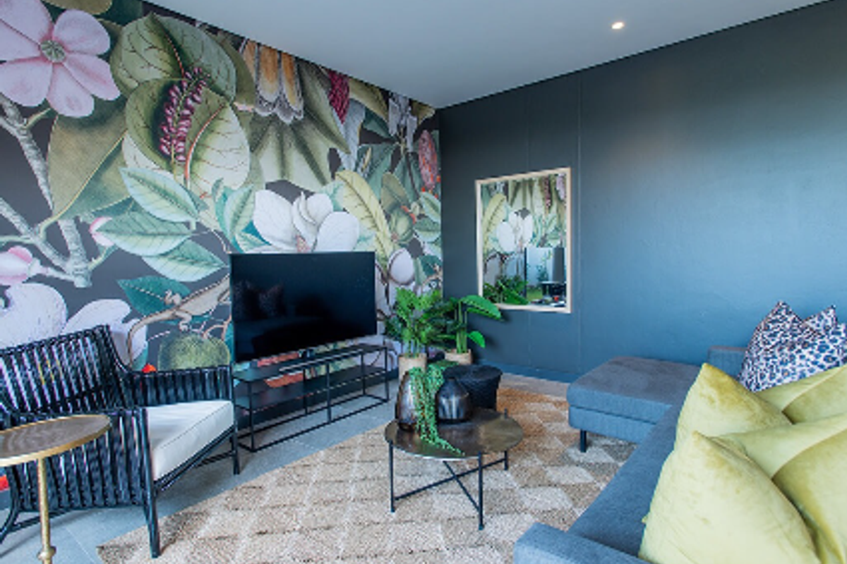 A modern living room featuring a bold floral feature wall, recessed downlighting, and a contemporary dark color palette.