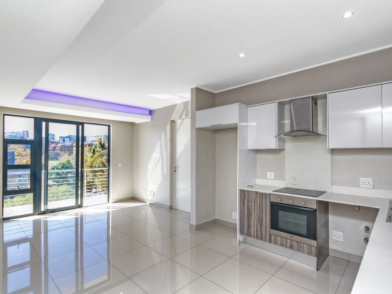 Modern open-plan kitchen and living area featuring sleek cabinetry, built-in appliances, polished floor tiles, and large sliding doors leading to a balcony.