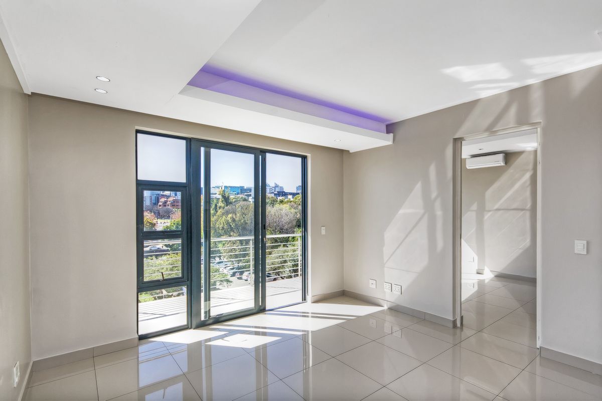 Bright and modern open-plan living area featuring sleek tiled floors, recessed LED ceiling lighting, and large sliding doors leading to a balcony with city views.