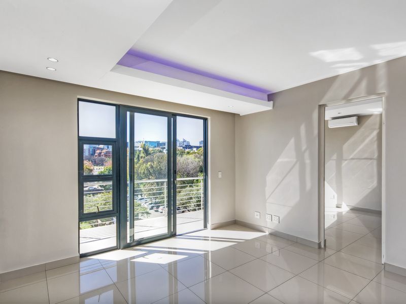 Bright and modern open-plan living area featuring sleek tiled floors, recessed LED ceiling lighting, and large sliding doors leading to a balcony with city views.