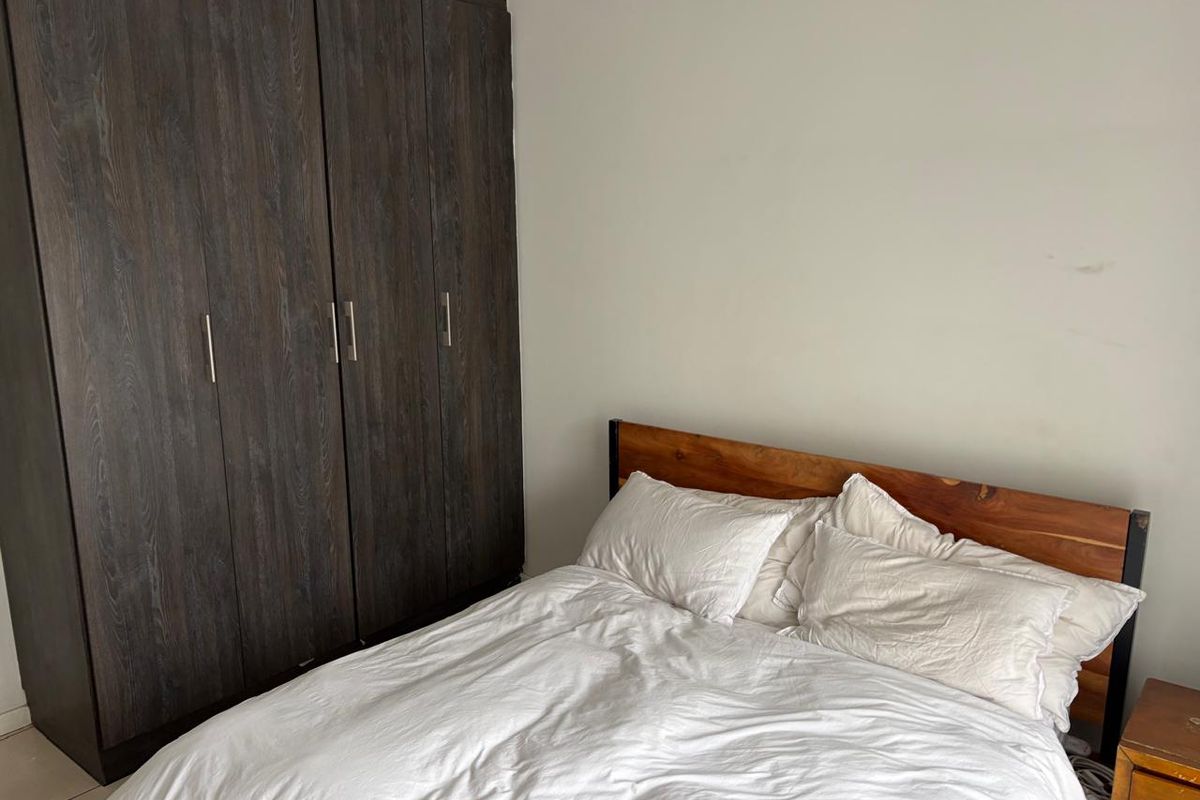 A bedroom featuring a dark wood-finish built-in wardrobe providing ample storage space.
