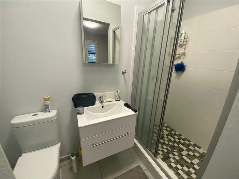A functional bathroom featuring a modern wall-mounted vanity, a mirror cabinet, and a glass-enclosed shower with tiled flooring.