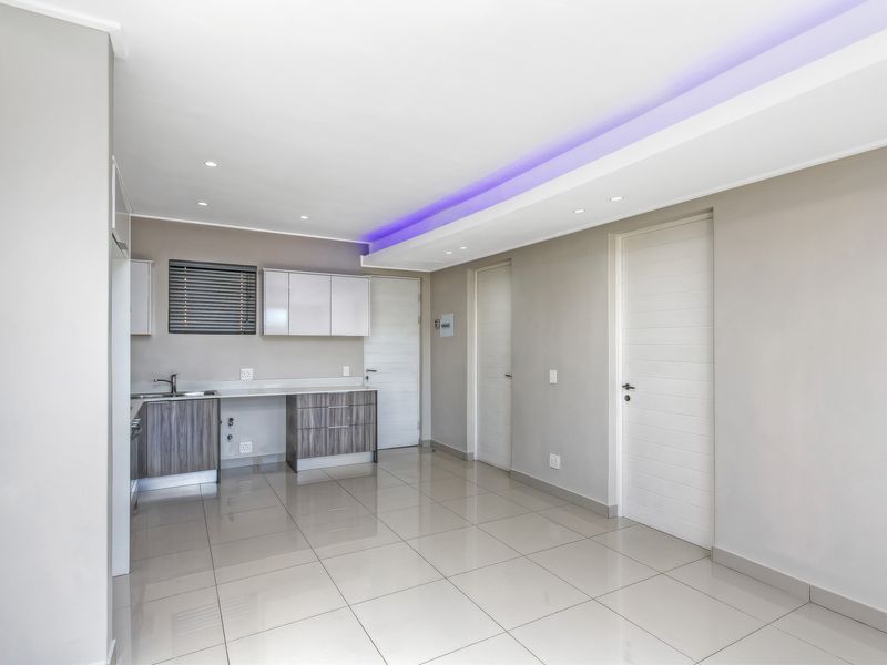 Modern open-plan living area featuring sleek cabinetry, tiled flooring, and contemporary recessed ceiling lighting with integrated LED accents.