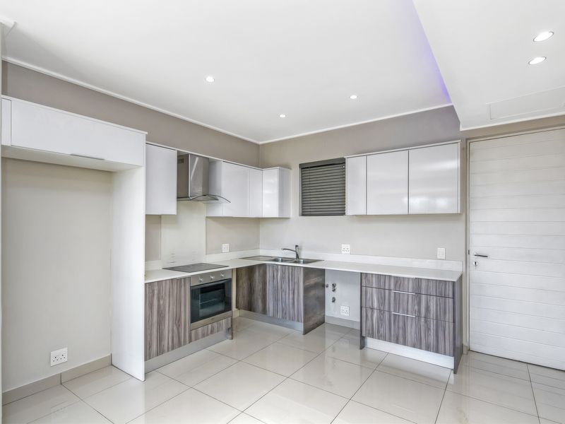Modern kitchen featuring sleek two-tone cabinetry, built-in oven, electric hob, extractor fan, and polished porcelain floor tiles in a clean, contemporary layout.