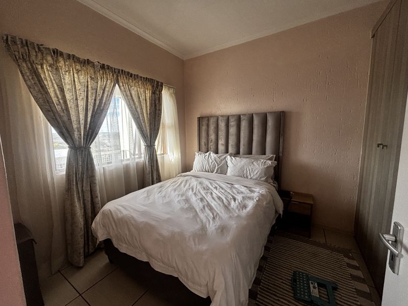 A functional bedroom featuring tiled flooring, a built-in wardrobe, and textured wall finishes, offering a comfortable space with natural light.