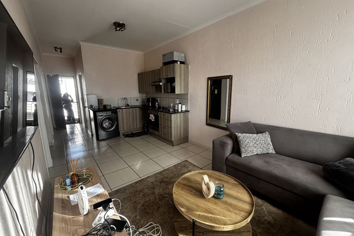 Open-plan living area featuring a compact kitchen with built-in cabinetry, oven, hob, and extractor fan, seamlessly connected to the lounge space.