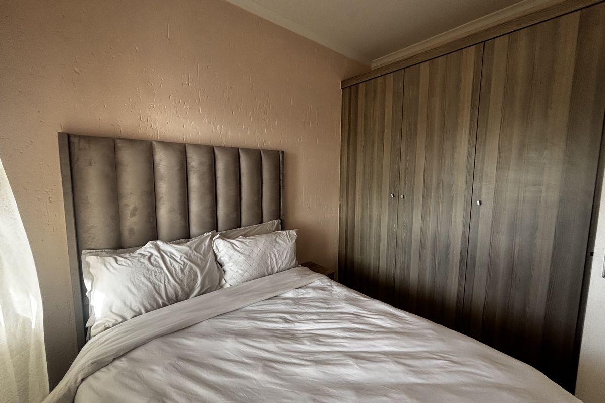 A bedroom featuring built-in wooden cupboards and textured wall finishes, providing functional storage space.