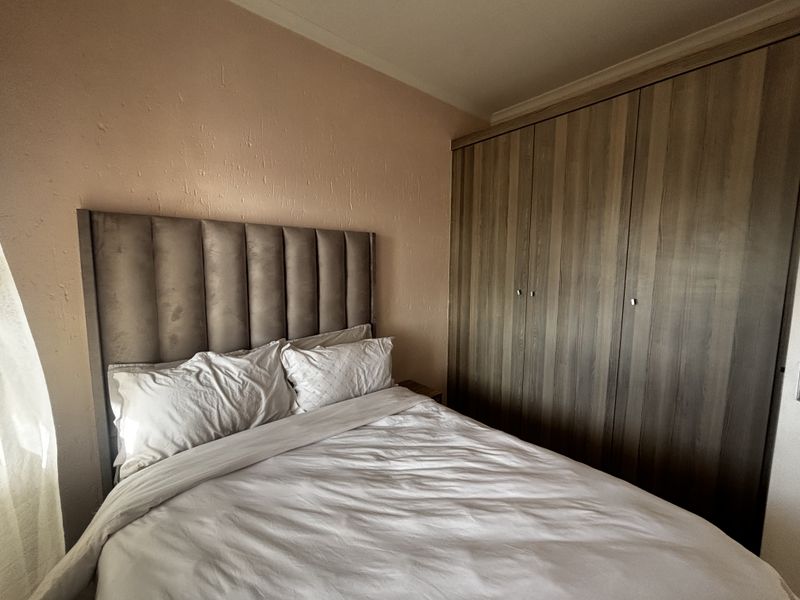 A bedroom featuring built-in wooden cupboards and textured wall finishes, providing functional storage space.