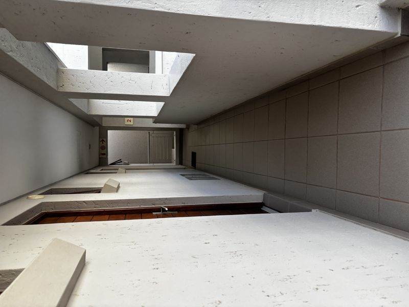 A functional apartment hallway featuring tiled flooring and open-air architectural design with access to unit entrances.