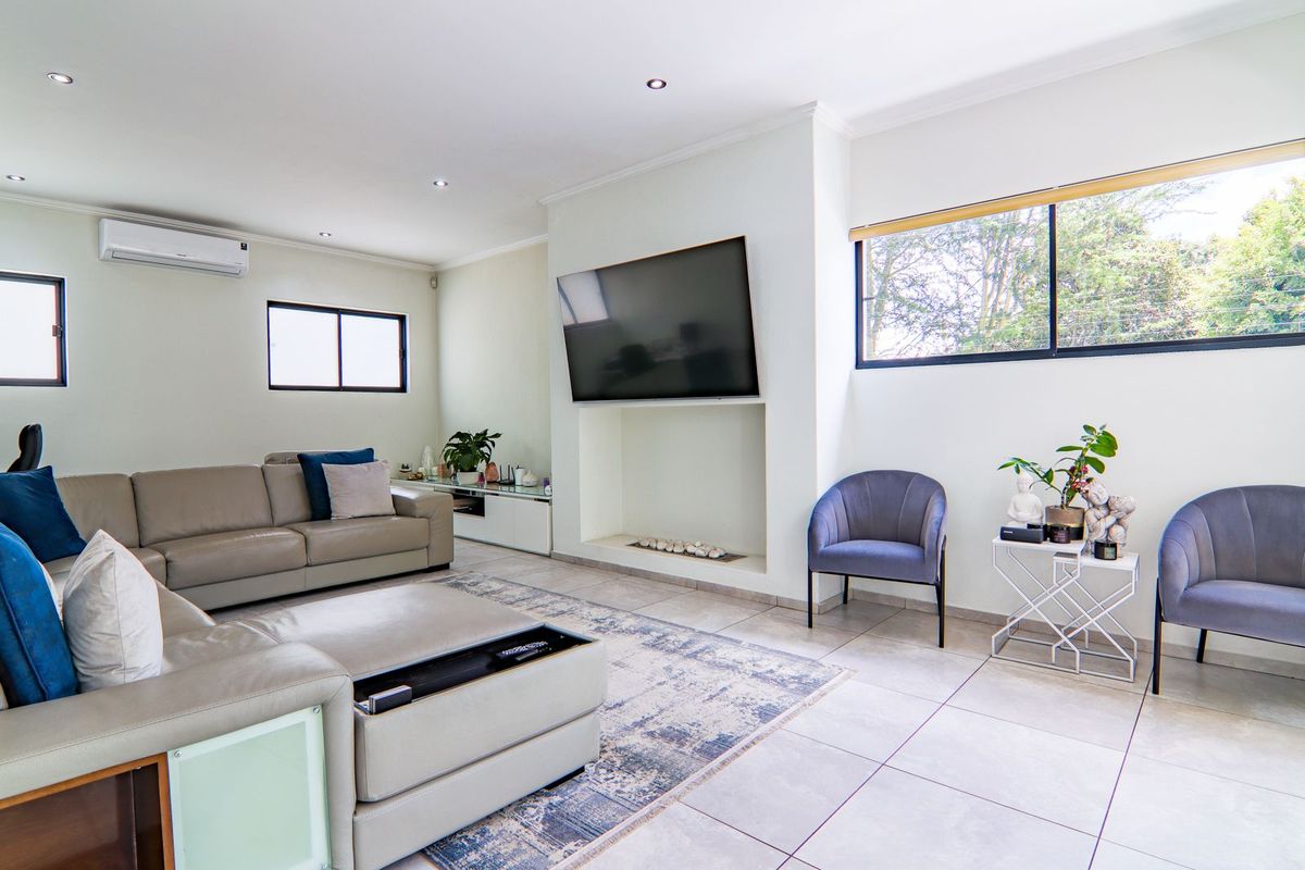 A bright and modern living room featuring tiled floors, a recessed fireplace, and a wall-mounted air conditioning unit.