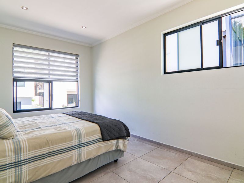 A bedroom featuring tiled flooring, recessed downlights, and dual sliding windows, providing a neutral foundation for interior design.