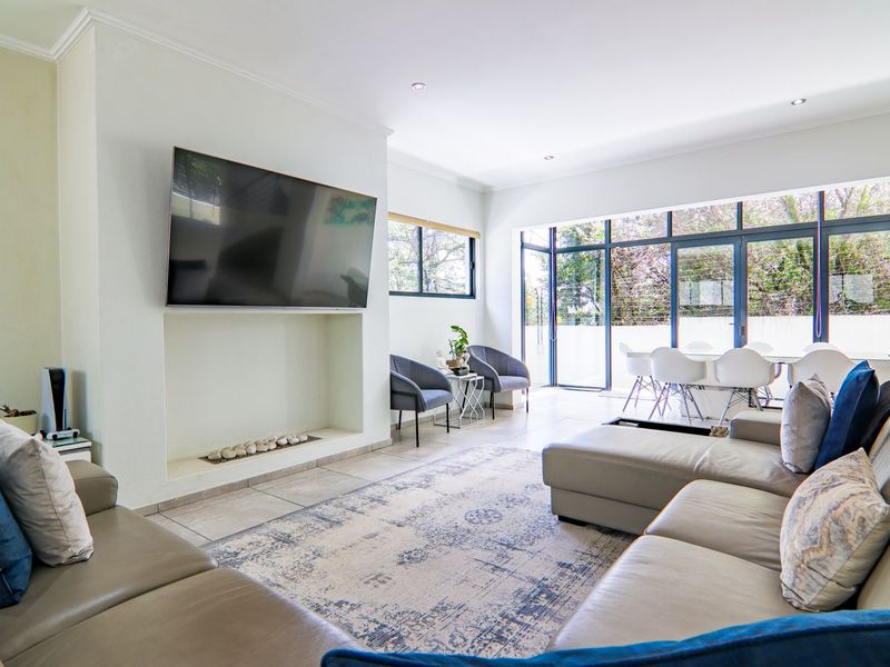 Spacious open-plan living area featuring tiled floors, a recessed fireplace, and large aluminium sliding doors providing ample natural light and garden access.