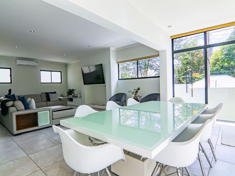 Spacious open-plan living and dining area featuring large format floor tiles, recessed lighting, and expansive glass doors providing ample natural light.