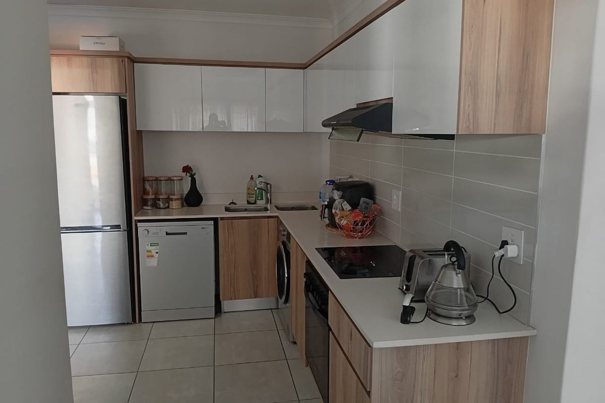 Modern kitchen featuring two-tone cabinetry, laminate countertops, integrated appliances, and tiled flooring, offering a clean and functional workspace.