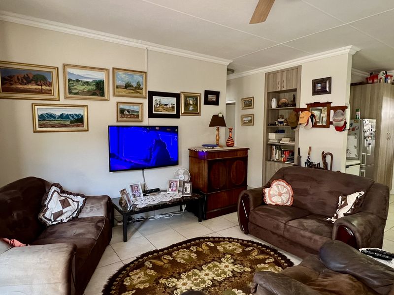 Open plan living area featuring tiled flooring, ceiling fan, and built-in shelving, providing a functional and connected space for relaxation.