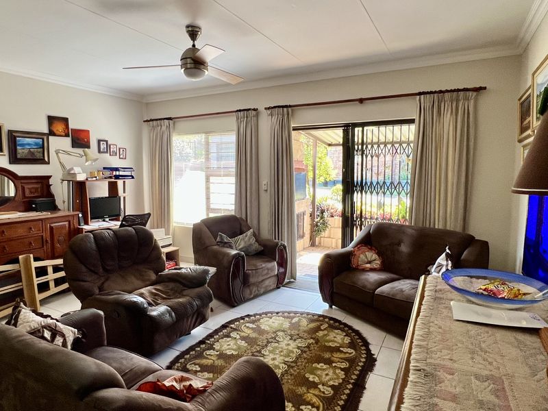 A comfortable living room featuring tiled flooring, a ceiling fan, and a sliding glass door providing access to an outdoor patio area.