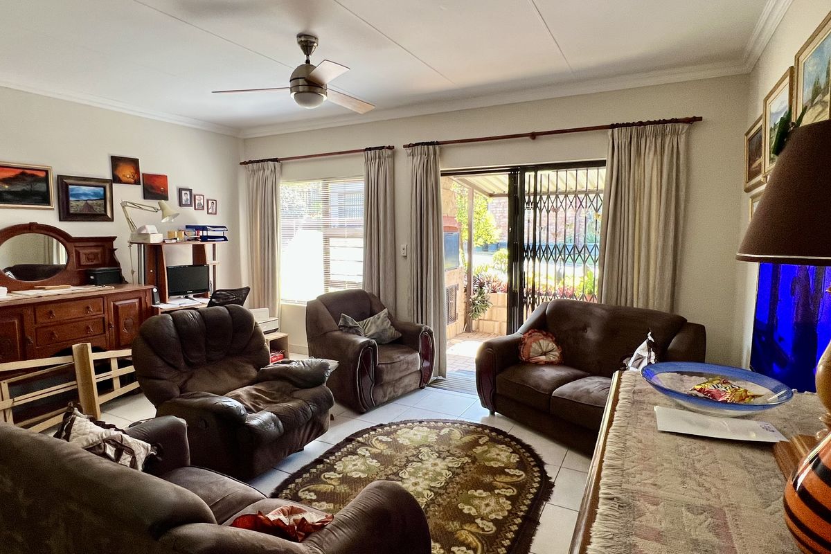 A comfortable living room featuring tiled flooring, a ceiling fan, and a sliding glass door providing access to an outdoor patio area.