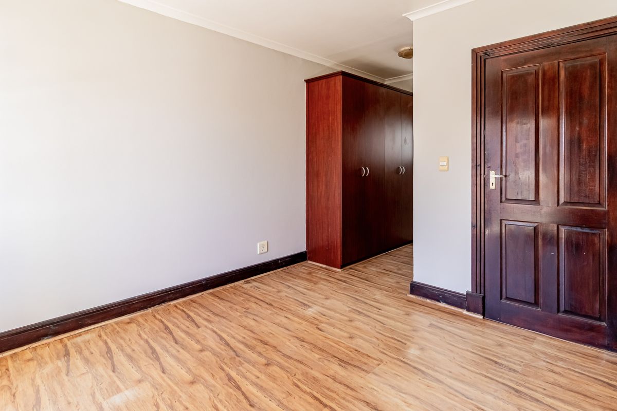 A vacant bedroom featuring laminate flooring, a built-in wardrobe, and a solid timber door.