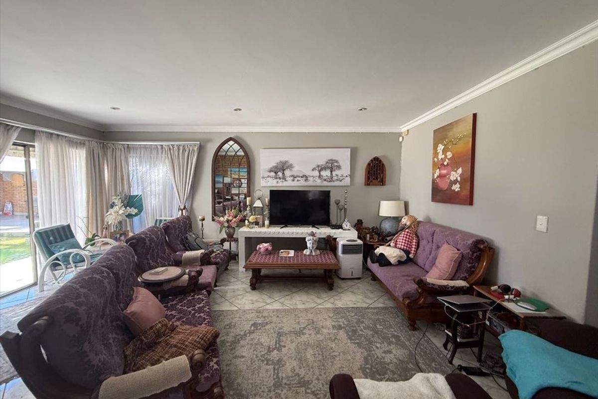 A spacious living room featuring tiled flooring, recessed downlighting, and large sliding glass doors that provide access to the outdoor area.