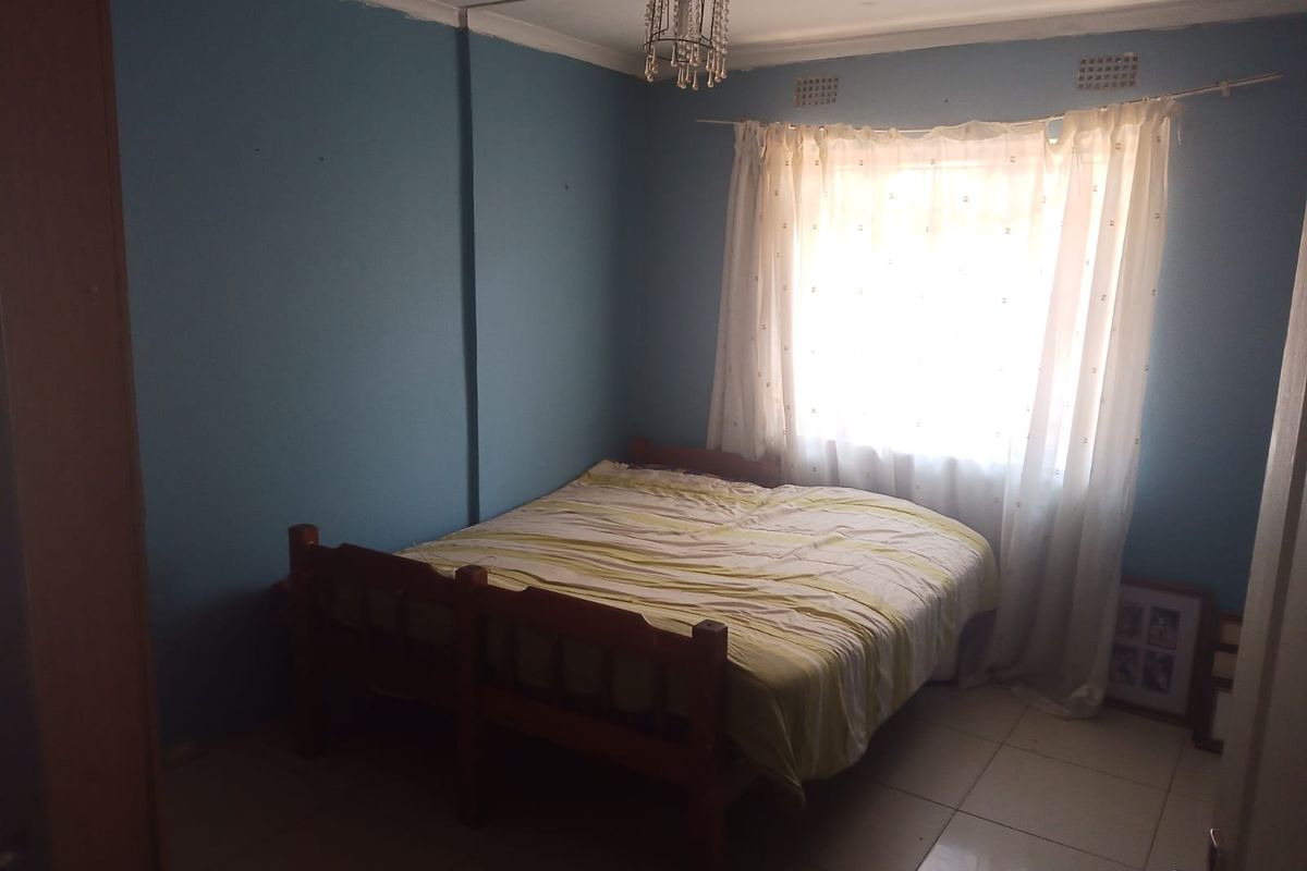 A bedroom featuring tiled flooring and a central light fixture, requiring cosmetic updates to the wall finishes to improve the overall aesthetic.