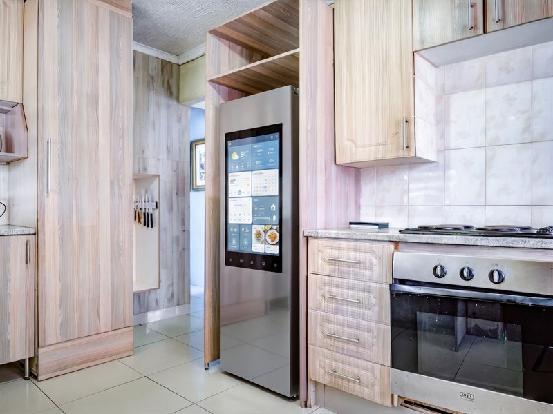 A functional kitchen featuring light wood-grain cabinetry, a tiled backsplash, built-in oven and hob, and tiled flooring.
