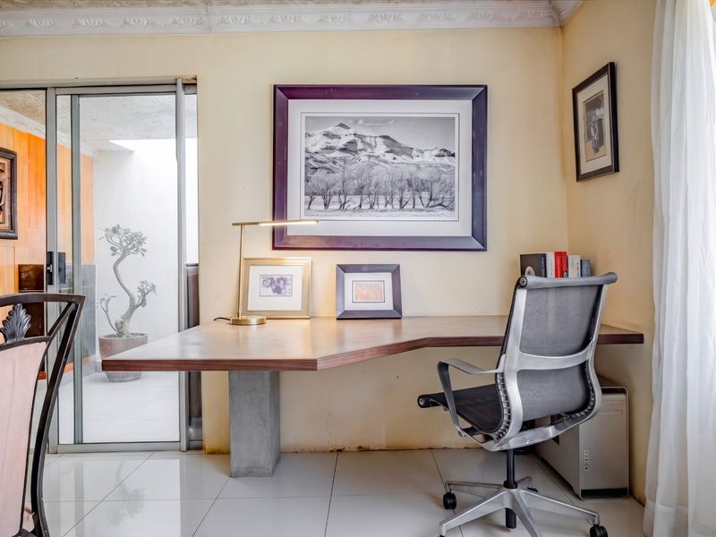 A home office space featuring a built-in desk, tiled flooring, and a sliding glass door providing access to an outdoor area.