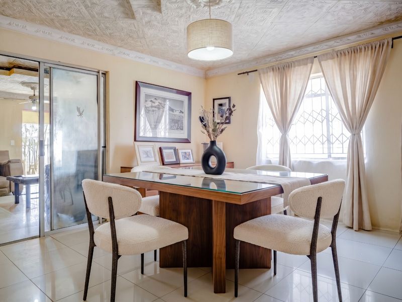 Dining room featuring tiled flooring, a textured ceiling with decorative cornice, and a sliding glass door leading to an adjacent space.