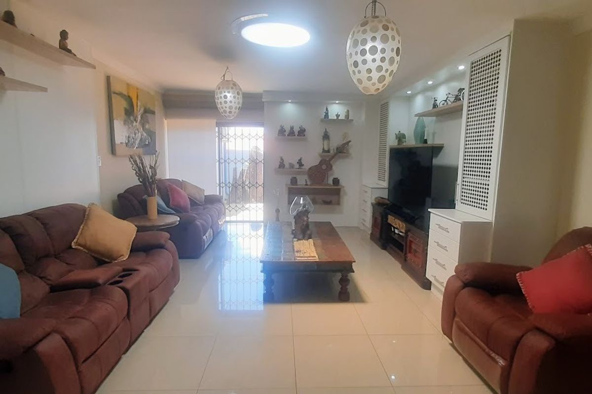 A comfortable living room featuring polished tiled flooring, built-in cabinetry for storage and media, and direct access to an outdoor area via a security gate.