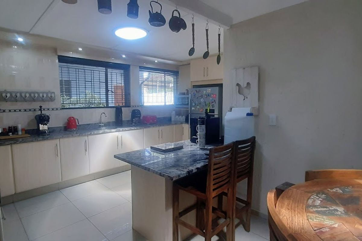 A functional kitchen featuring granite countertops, ample built-in cabinetry, a central island, and tiled flooring, providing a practical workspace for daily cooking.